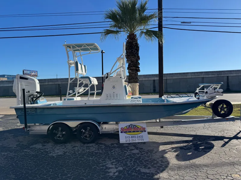 The Image of 2025 Shallow Sport 24 Sport boat on trailer, parked near palm tree. - 0
