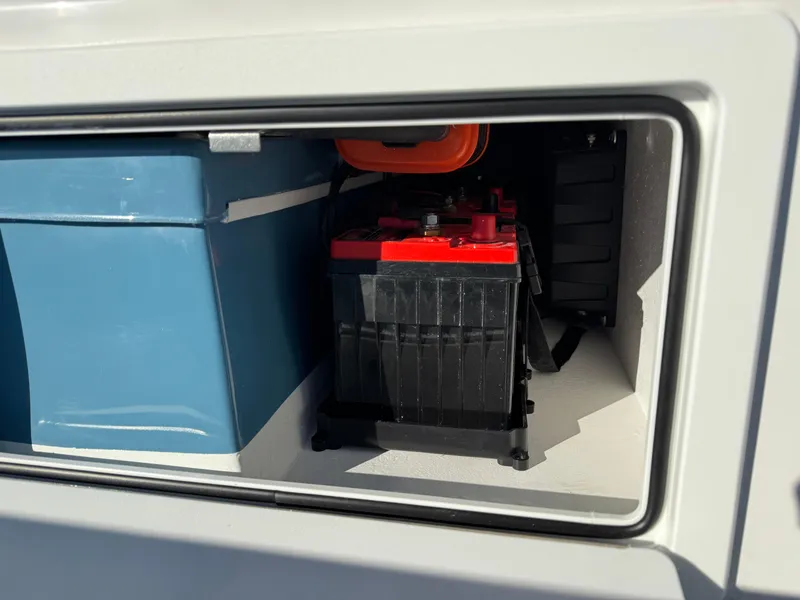 Slide: The Image of 2025 Shallow Sport 24 Sport boat storage compartment with battery and equipment. - 11