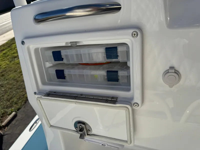 Slide: The Image of 2025 Shallow Sport 24 Sport boat storage compartment with tackle boxes. - 15