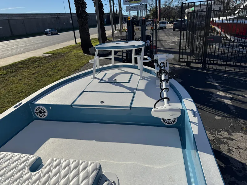 Slide: The Image of 2025 Shallow Sport 24 Sport boat with trolling motor and seating, parked outdoors. - 24