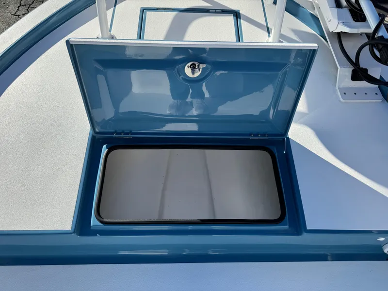 Slide: The Image of 2025 Shallow Sport 24 Sport boat storage compartment, open lid, blue and white design. - 26