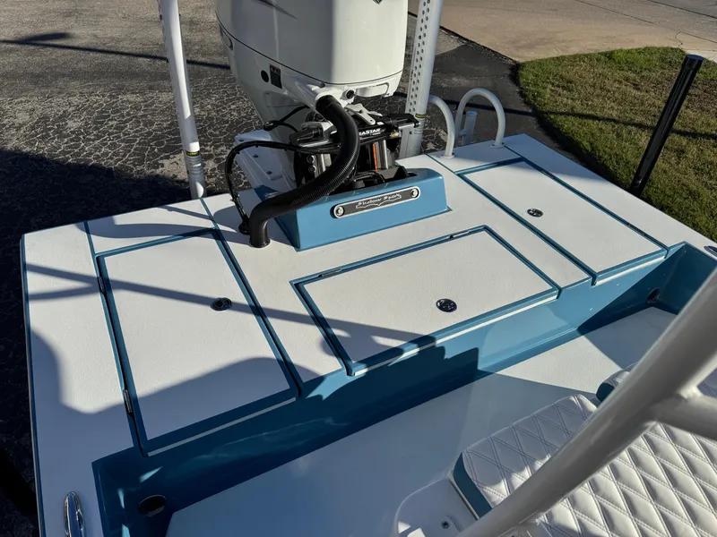 Slide: The Image of 2025 Shallow Sport 24 Sport boat deck with engine, featuring blue and white design. - 32