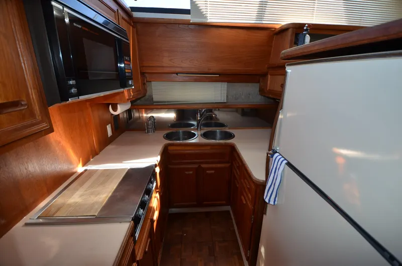 Slide: The Image of 1987 Carver 4207 yacht kitchen with wood cabinetry, double sink, and modern appliances. - 11
