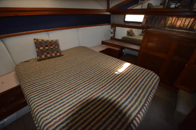 Slide: The Image of 1987 Carver 4207 yacht bedroom with striped bedding and wooden cabinetry. - 21