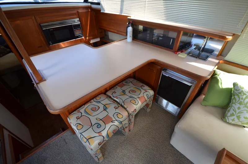 Slide: The Image of 1987 Carver 4207 yacht interior with kitchen counter, stools, and seating area. - 25