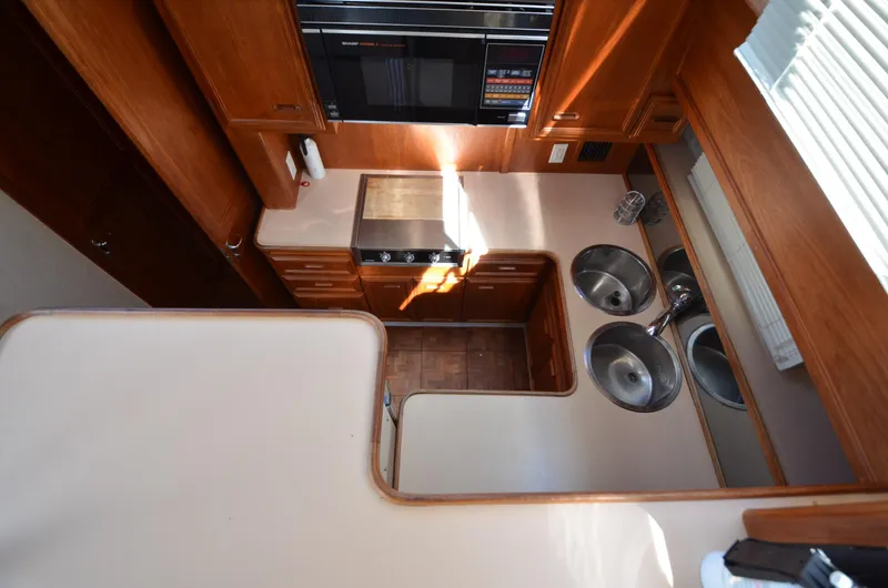 Slide: The Image of 1987 Carver 4207 yacht kitchen with stove, microwave, and dual sinks, featuring wood cabinetry. - 26