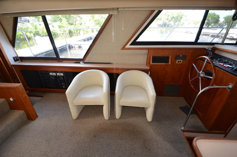 Slide: The Image of 1987 Carver 4207 yacht interior with white chairs, steering wheel, and large windows. - 27