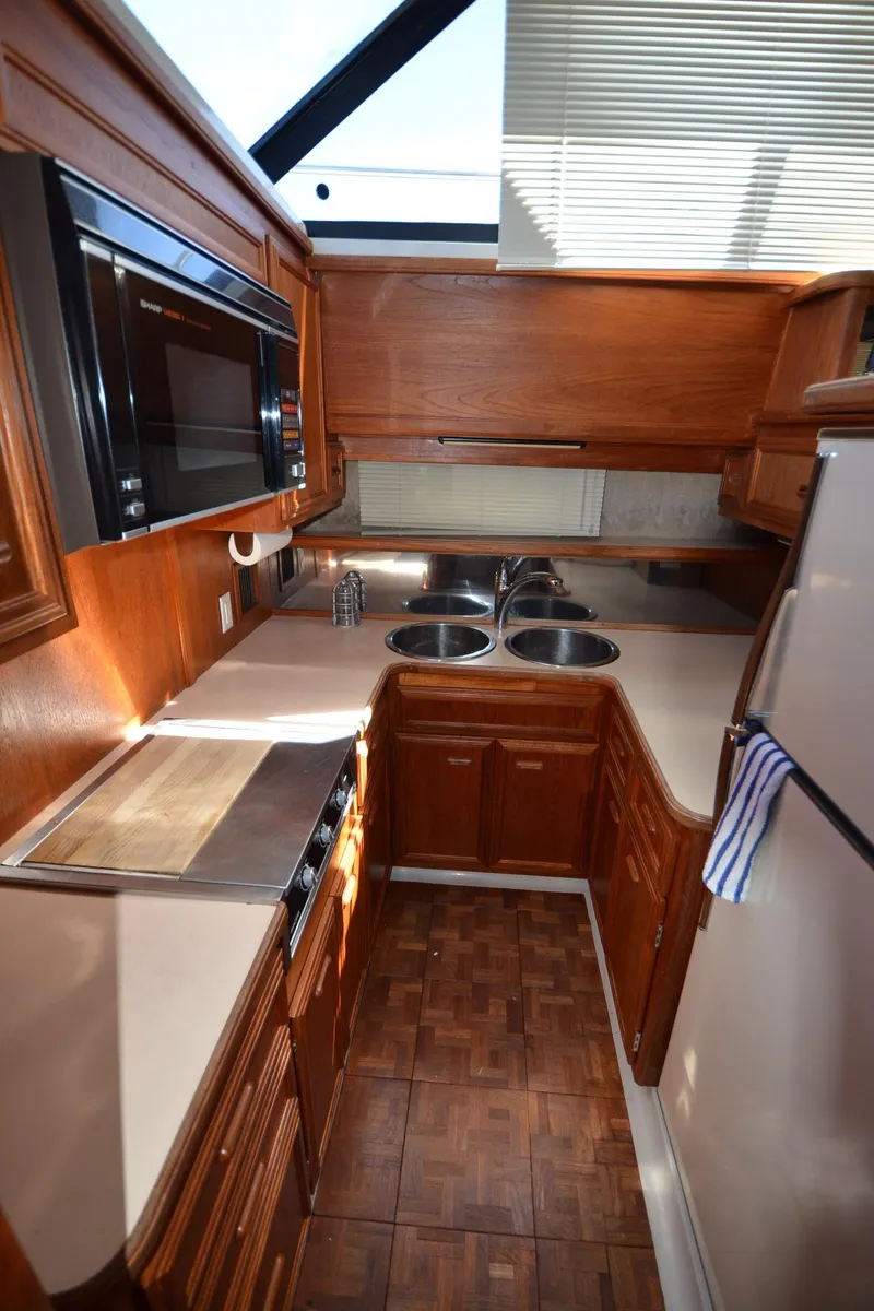 Slide: The Image of 1987 Carver 4207 yacht kitchen with wood cabinetry, dual sinks, microwave, and refrigerator. - 36