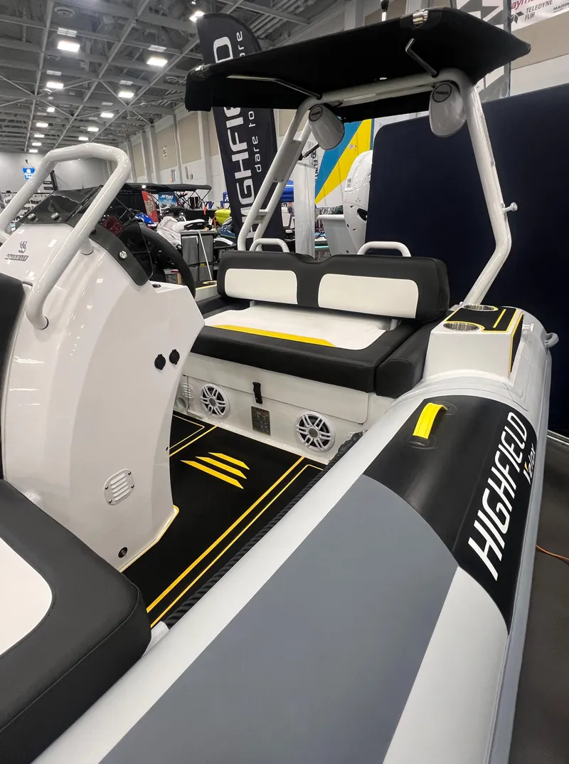 Slide: The Image of 2025 Highfield Velox 420 boat interior with seating and control console at a boat show. - 2