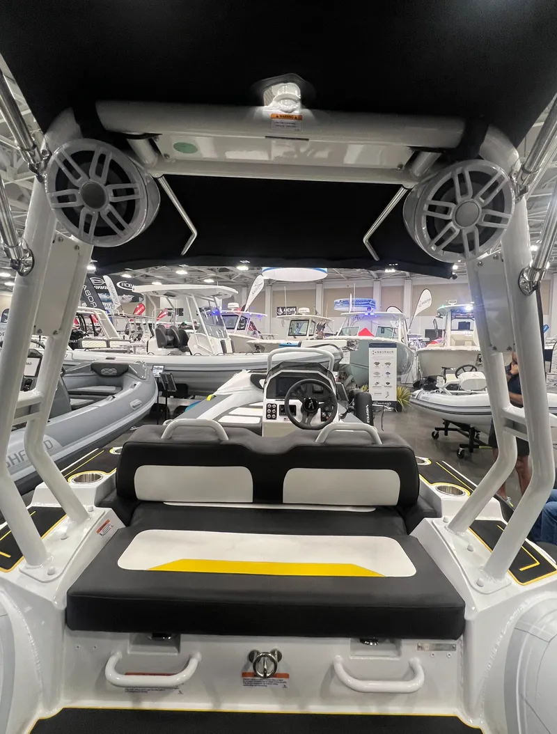 Slide: The Image of 2025 Highfield Velox 420 boat interior with modern seating and steering console at a showroom. - 3