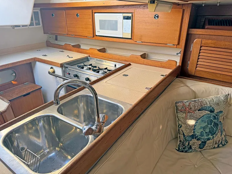 Slide: The Image of Catalina 36 MkII 2000 yacht kitchen with sink, stove, microwave, and turtle-themed pillow. - 13