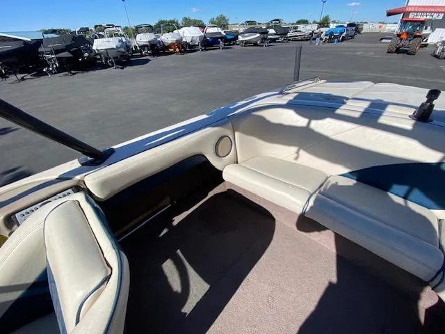 Slide: The Image of 2001 Nautique Super Air Nautique 210 interior with beige seating, parked among other boats. - 14