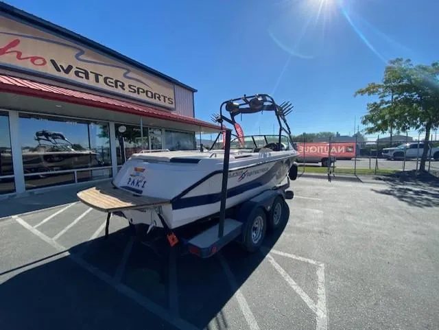 Slide: The Image of 2001 Nautique Super Air Nautique 210 boat on trailer outside water sports store. - 3