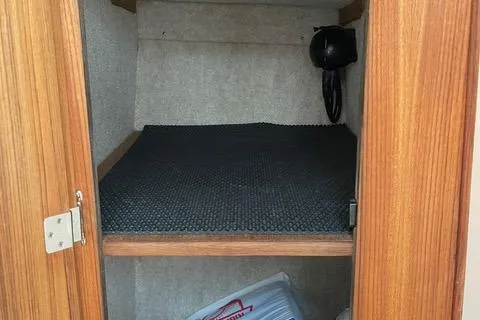 Slide: The Image of 2013 Carolina Classic 25 Express cabin storage with wooden door and black mat. - 10