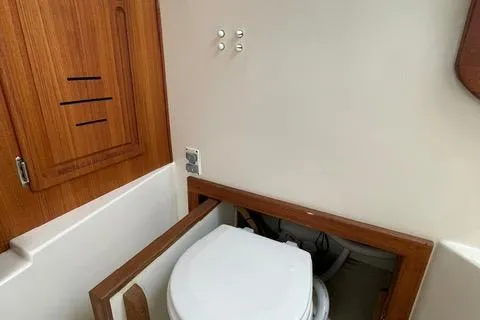 Slide: The Image of 2013 Carolina Classic 25 Express boat bathroom with wooden cabinetry and compact toilet. - 13