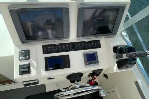 Slide: The Image of 2013 Carolina Classic 25 Express boat dashboard with dual screens and controls. - 2