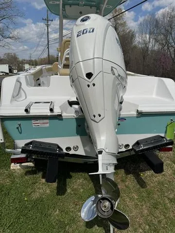 Slide: The Image of 2024 Sportsman Open 212 boat with powerful outboard motor, parked on grass. - 7