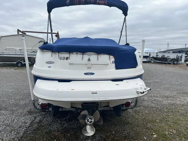 Slide: The Image of 2005 Chaparral Sunesta 236 boat, rear view with blue cover, parked on gravel. - 4