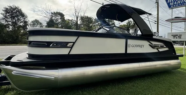 Slide: The Image of 2025 Godfrey AP235 ULW pontoon boat on grass, sleek design, black and white exterior. - 3