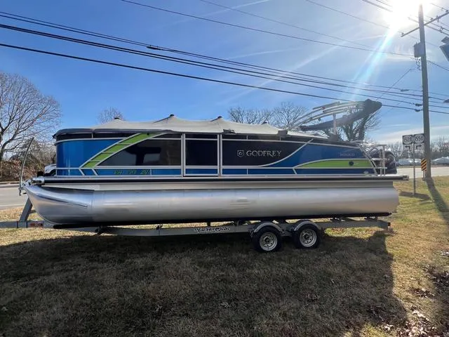 Slide: The Image of 2022 Godfrey Monaco 235 SFL pontoon boat on trailer, parked on grass under sunny sky. - 17