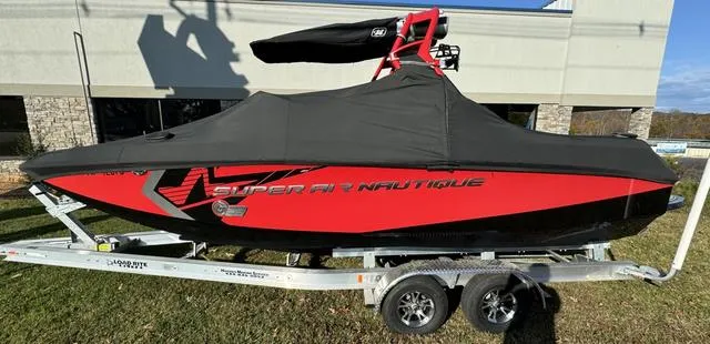 Slide: The Image of 2014 Nautique Super Air G23 boat, red and black, on a trailer, covered and parked outdoors. - 4