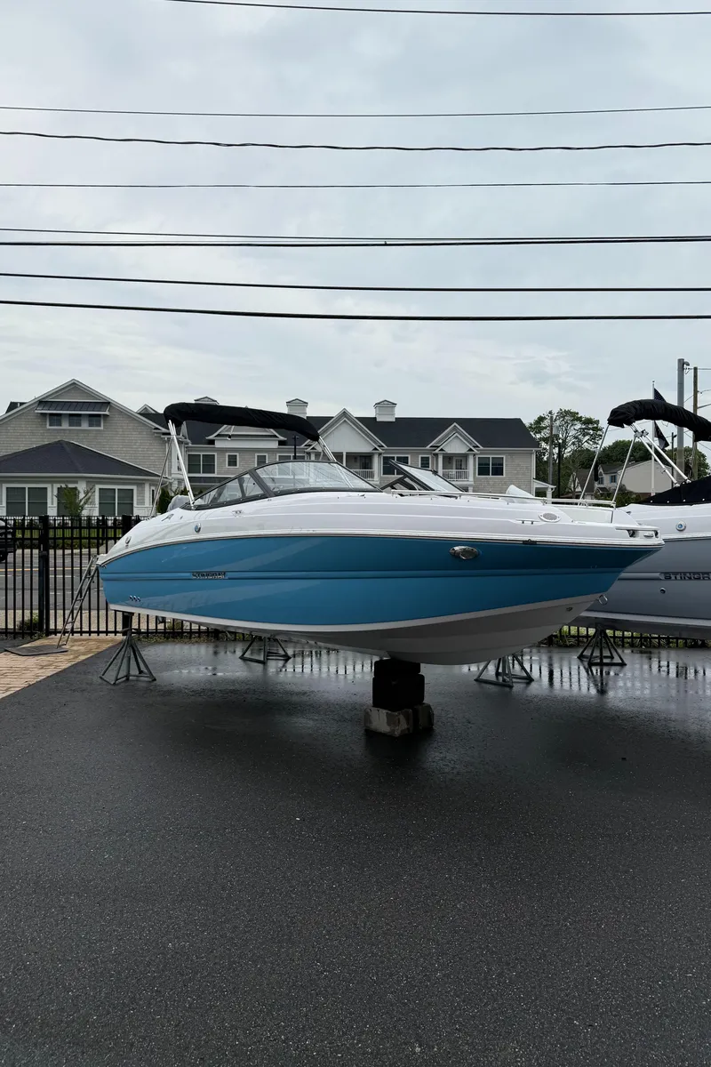 Slide: The Image of 2025 Stingray 211 DC boat displayed outdoors on a stand, with houses in the background. - 3