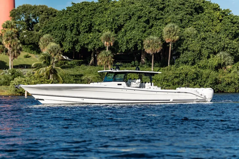 Slide: The Image of 2019 HCB 53 boat cruising on a scenic waterway with lush greenery. - 5