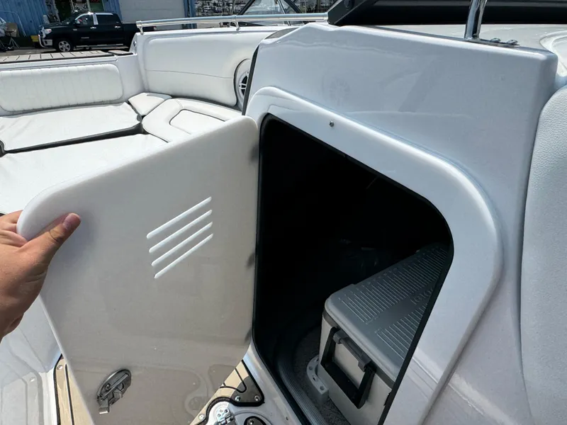 Slide: The Image of 2025 Stingray 211 DC boat storage compartment with cooler, open door view. - 17