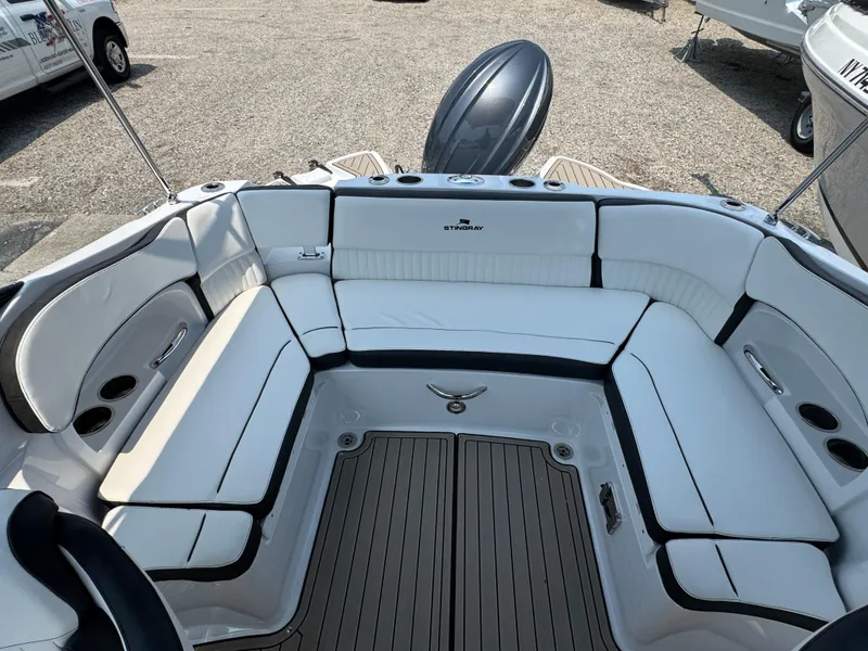 Slide: The Image of 2025 Stingray 211 DC boat interior with white seating and wood-style flooring. - 2