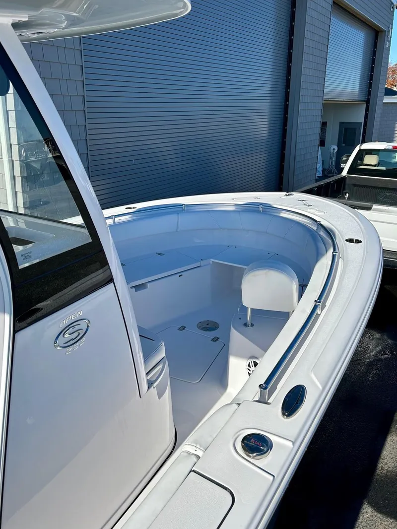 Slide: The Image of 2024 Sportsman Open 232 Center Console boat, sleek design, docked near a building. - 19