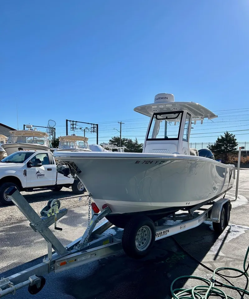Slide: The Image of 2024 Sportsman Open 232 Center Console boat on trailer in sunny marina. - 2