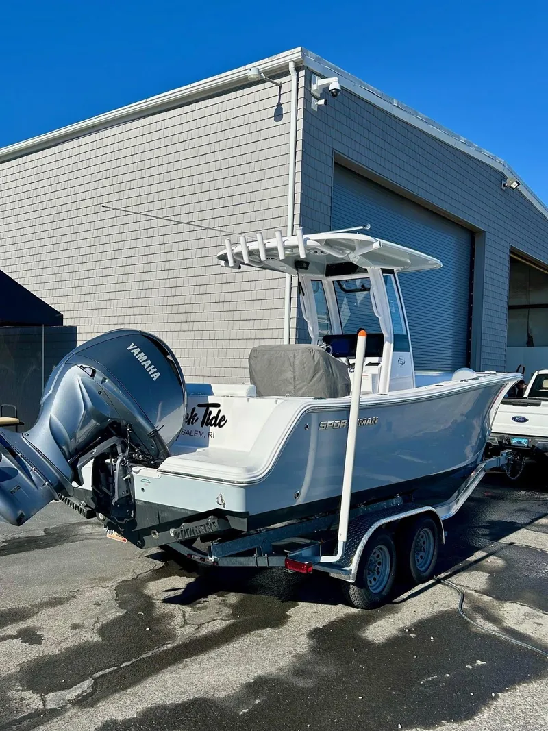 Slide: The Image of 2024 Sportsman Open 232 Center Console boat on trailer, parked outside a warehouse. - 4