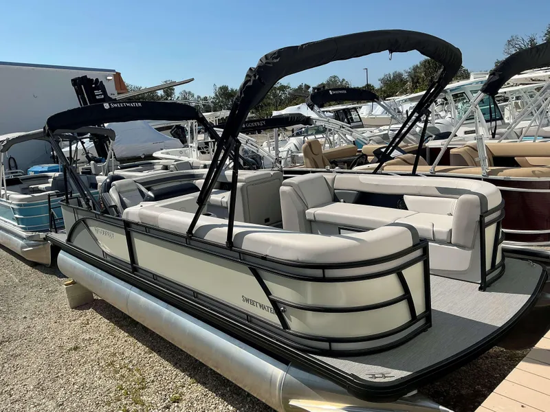 Slide: The Image of 2025 Sweetwater 2286 C pontoon boat with spacious seating and canopy, docked outdoors. - 1