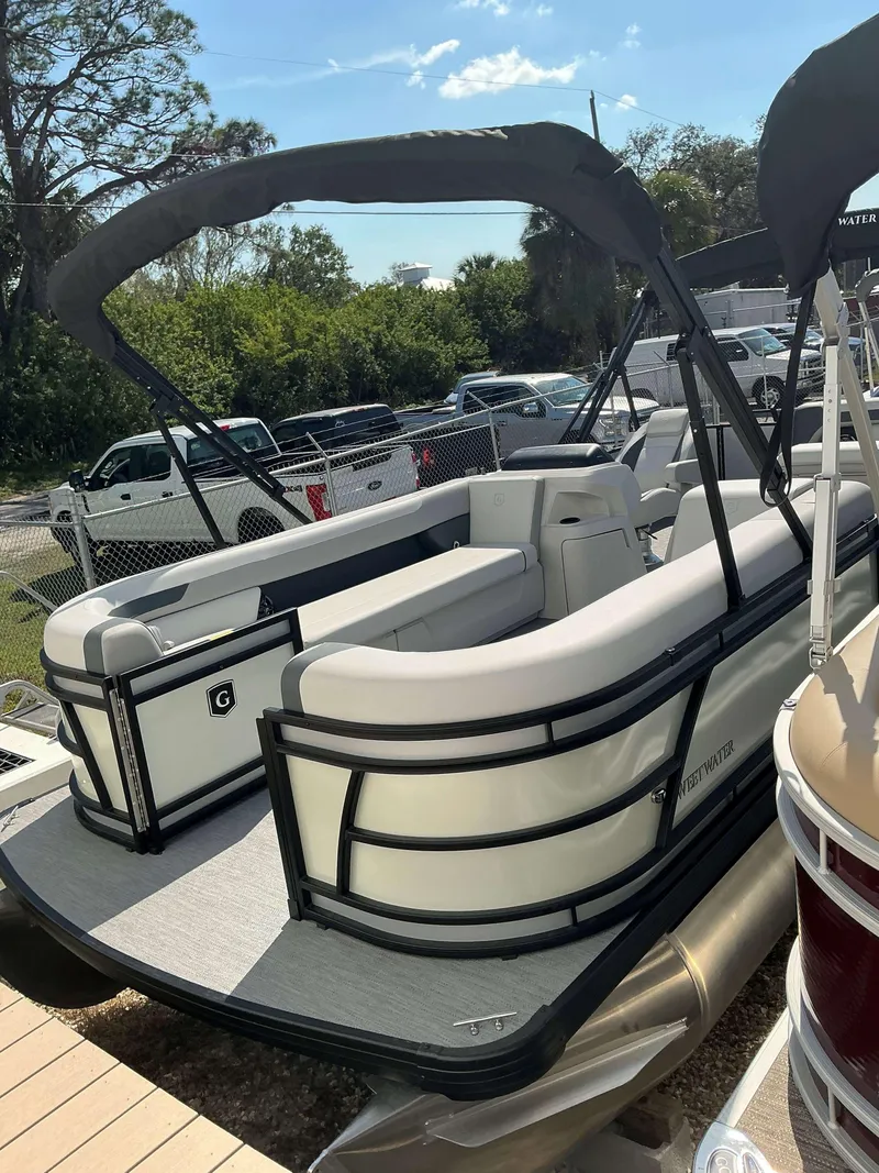 Slide: The Image of 2025 Sweetwater 2286 C pontoon boat with canopy, parked outdoors. - 3