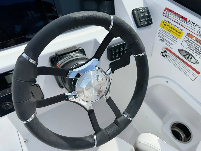 Slide: The Image of Steering wheel of 2025 Stingray 231 DC boat, featuring modern controls and safety labels. - 11
