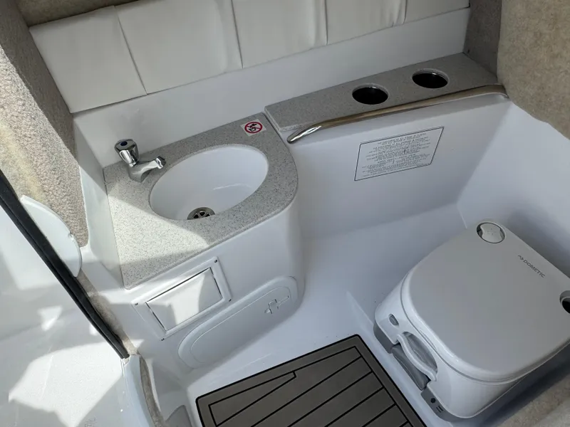 Slide: The Image of 2025 Stingray 231 DC boat interior with sink, toilet, and cup holders. - 13