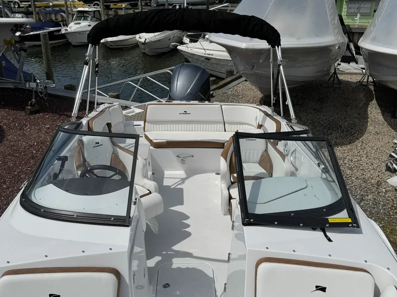Slide: The Image of 2025 Stingray 231 DC boat with open deck, dual consoles, and seating, docked at a marina. - 19