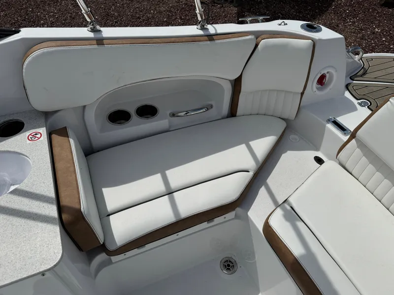 Slide: The Image of 2025 Stingray 231 DC boat interior with white and brown cushioned seating. - 2