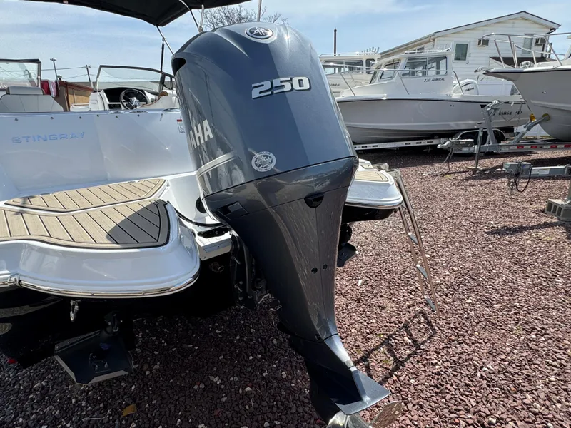 Slide: The Image of 2025 Stingray 231 DC boat with Yamaha 250 outboard motor, docked on gravel. - 20