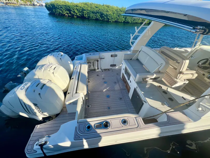Slide: The Image of 2018 Boston Whaler 350 Realm boat with triple engines, spacious deck, and seating area. - 2