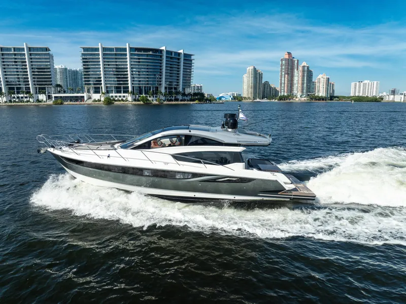 The Image of 2016 Galeon 430 HTC yacht cruising near modern waterfront buildings. - 0