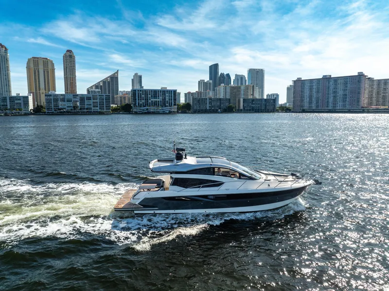 Slide: The Image of Galeon 430 HTC yacht cruising on water with city skyline in background, 2016 model. - 2