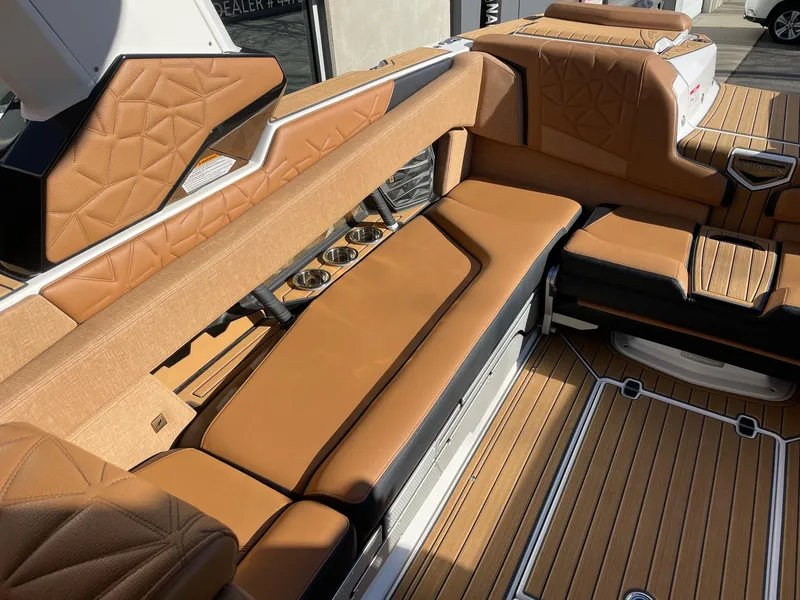 Slide: The Image of 2023 Nautique Super Air Nautique G25 Paragon interior with tan leather seating and cup holders. - 7