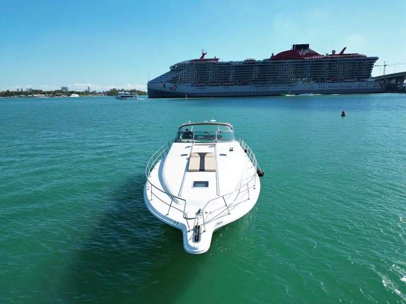 Slide: The Image of 1998 Sea Ray 500 Sundancer yacht on turquoise water, with a large cruise ship in the background. - 3