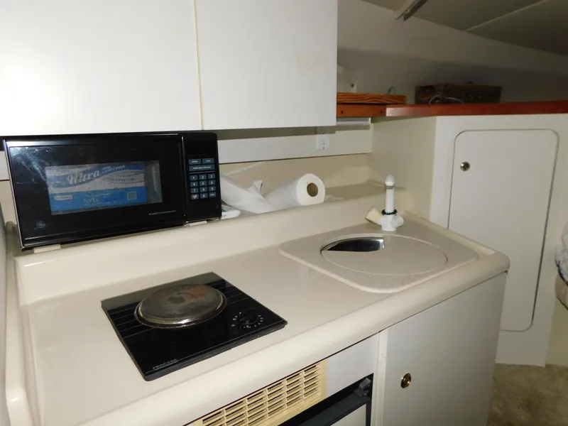 Slide: The Image of 1998 Cruisers 2870 Rogue boat kitchenette with microwave, stove, and sink. - 19
