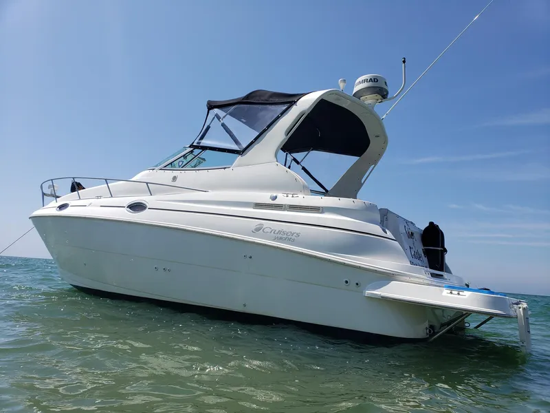 Slide: The Image of 1998 Cruisers 2870 Rogue boat on water, clear sky, side view. - 2