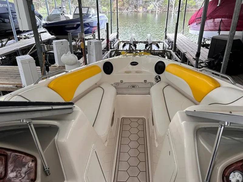 Slide: The Image of 2003 Rinker RX1 boat interior with yellow and white seating, docked by the water. - 2