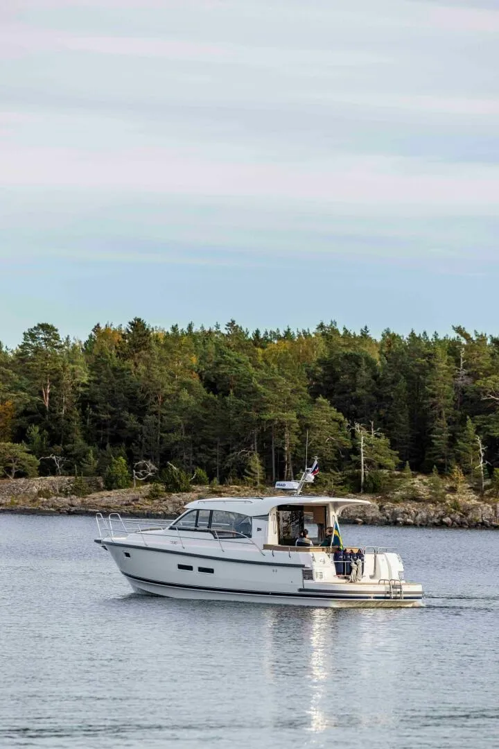 Slide: The Image of Nimbus 365 Coupe 2025 cruising on a serene lake with forested shoreline. - 4