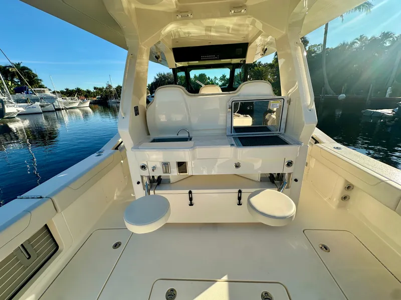 Slide: The Image of 2025 Scout 425 LXF boat interior with seating and storage, docked by the water. - 22