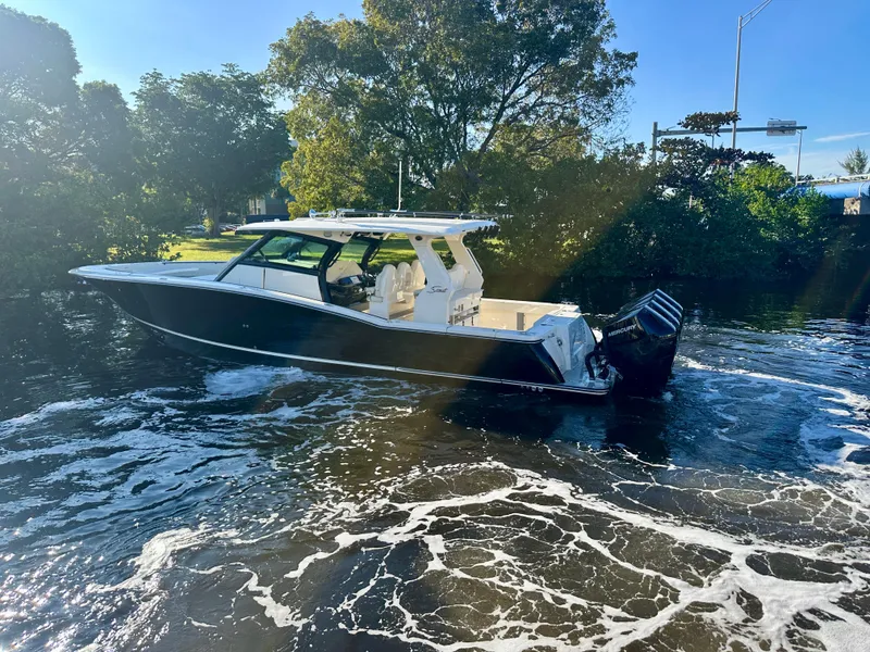 Slide: The Image of 2025 Scout 425 LXF boat cruising on a sunny day, surrounded by lush greenery. - 3